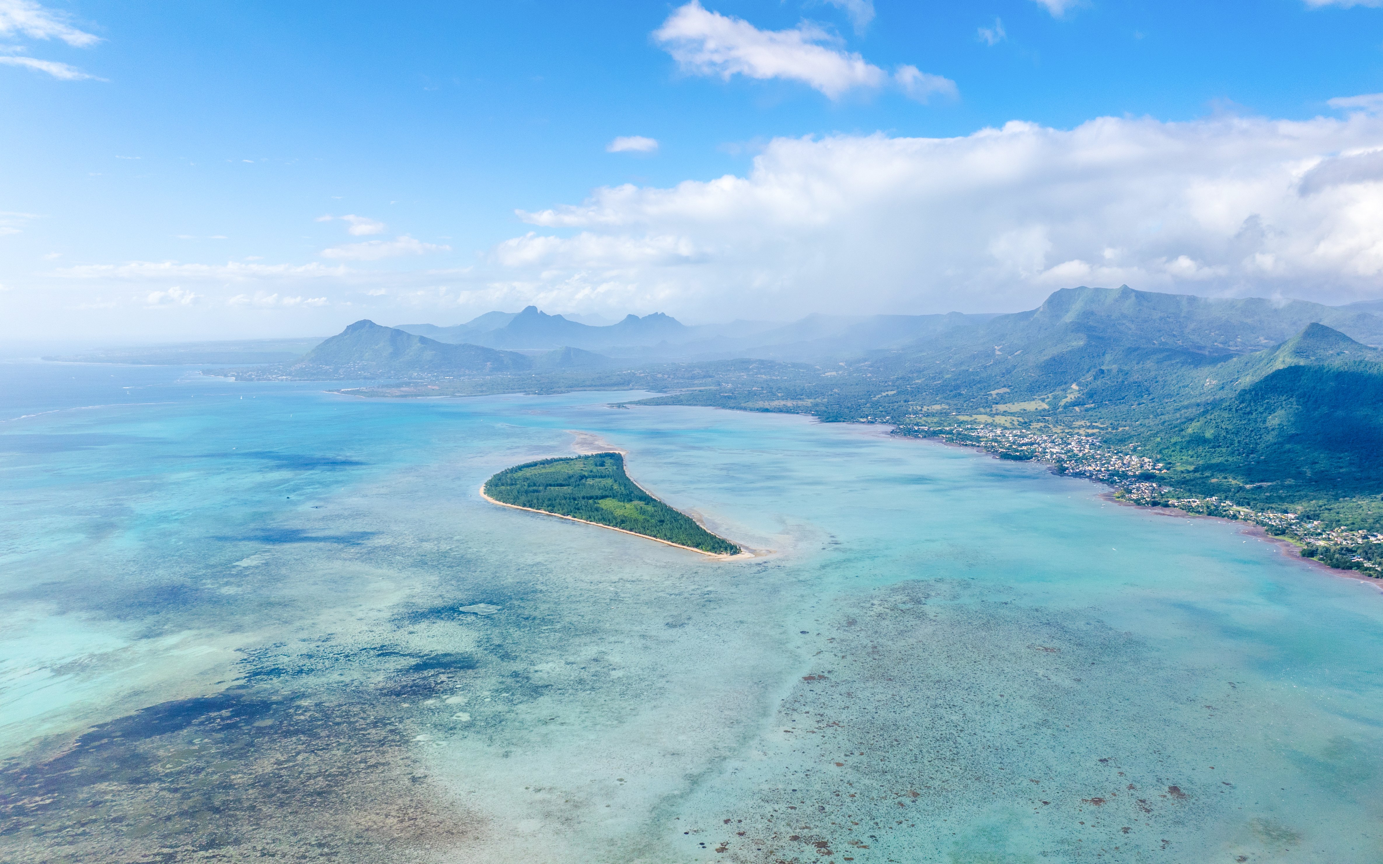Aerial view of Île aux Bénitiers surrounded by turquoise waters and distant mountains in Mauritius.