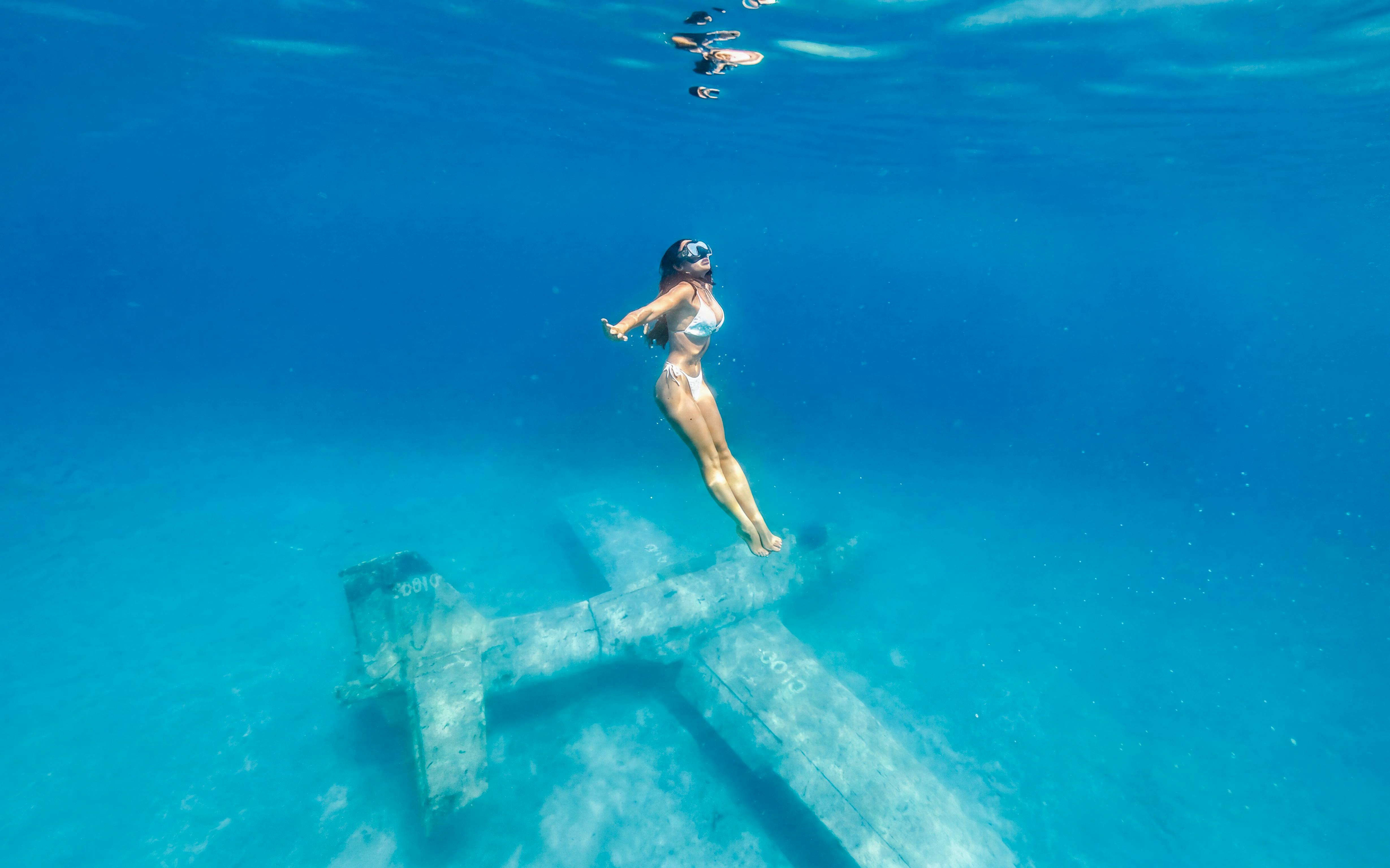Diver exploring underwater plane wreck at exclusive beach resort.
