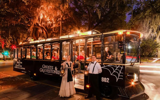 Ghosts & Gravestones tour trolley at night with costumed guides and passengers in Savannah.