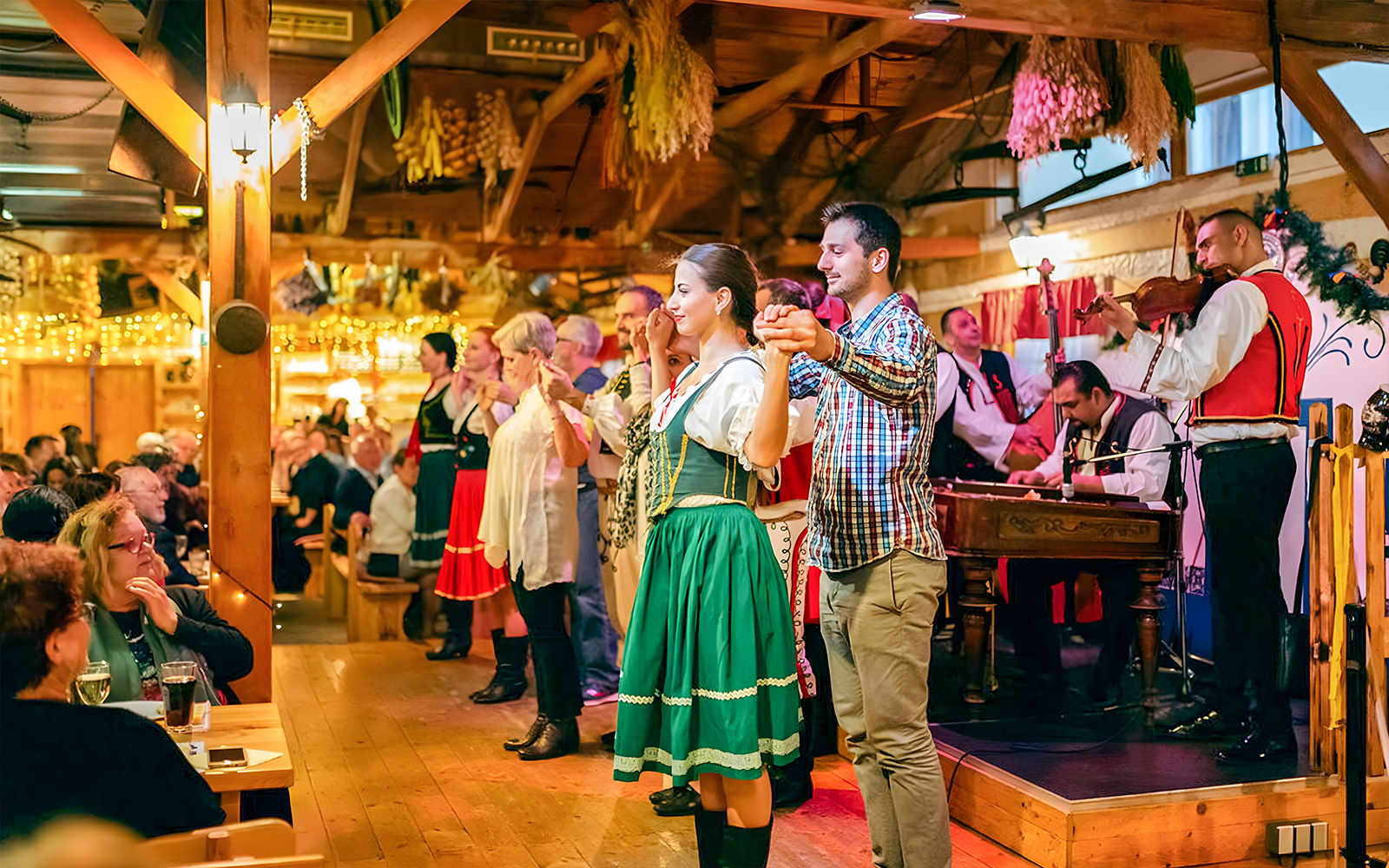 Folklore dancers performing at a Prague dinner show with live musicians.