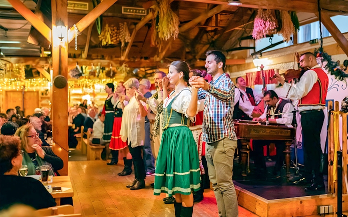 Folklore dancers performing at a Prague dinner show with live musicians.