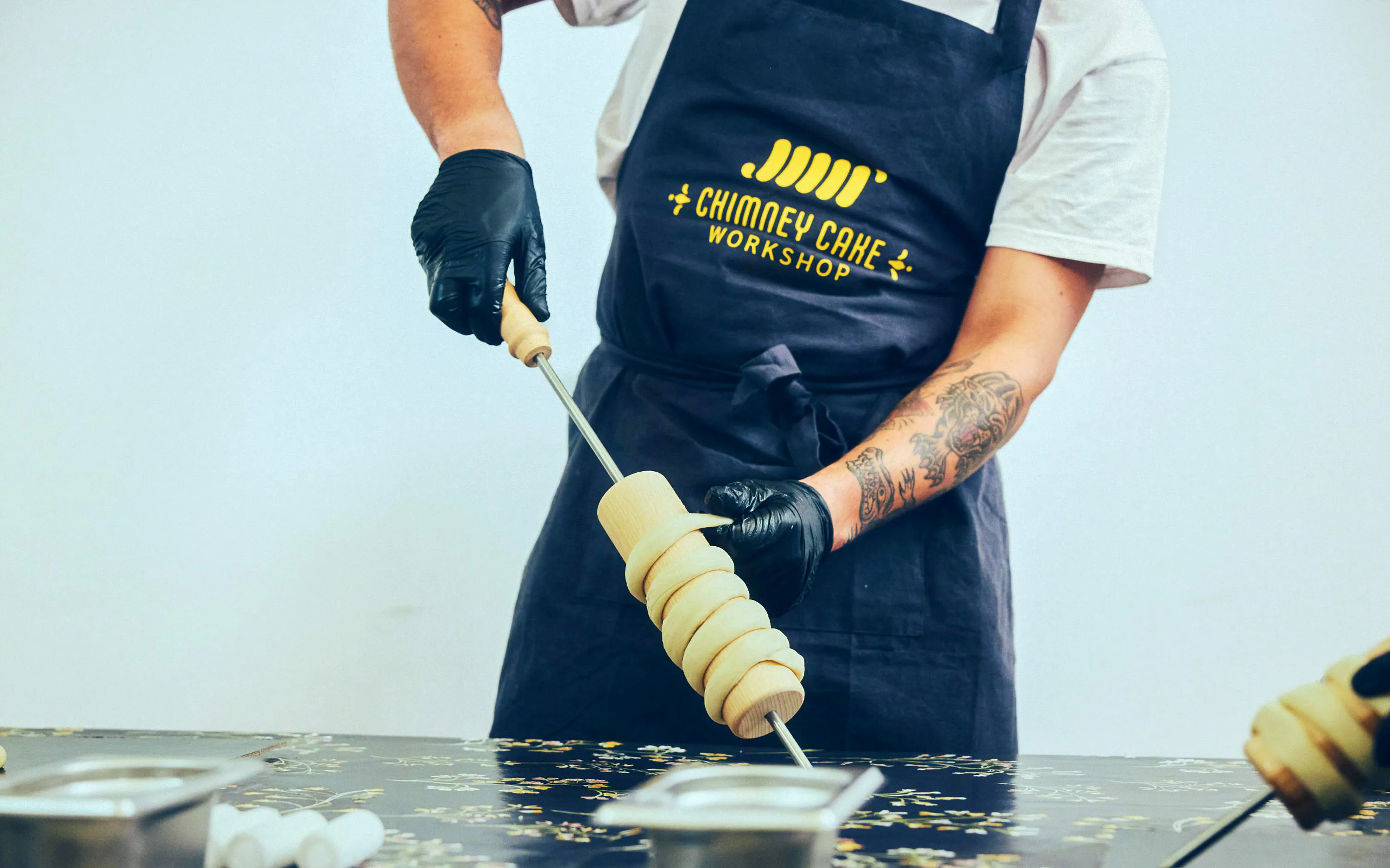 Rapping dough onto a wooden spit at a Chimney Cake Workshop in Budapest.