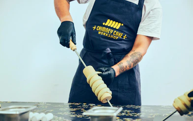 Rapping dough onto a wooden spit at a Chimney Cake Workshop in Budapest.