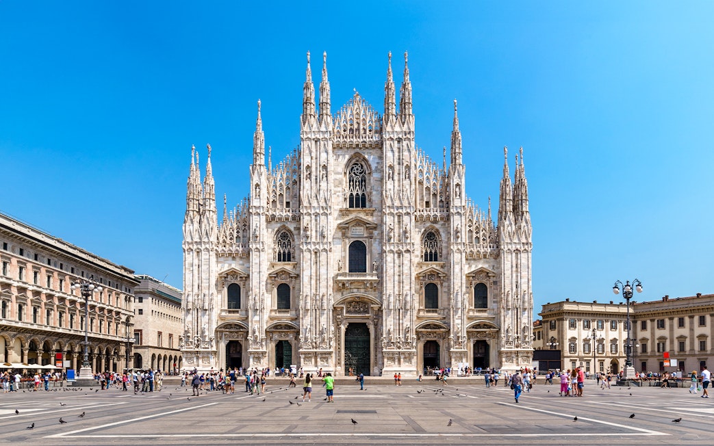 Milan Cathedral facade with tourists in Piazza del Duomo, Italy.
