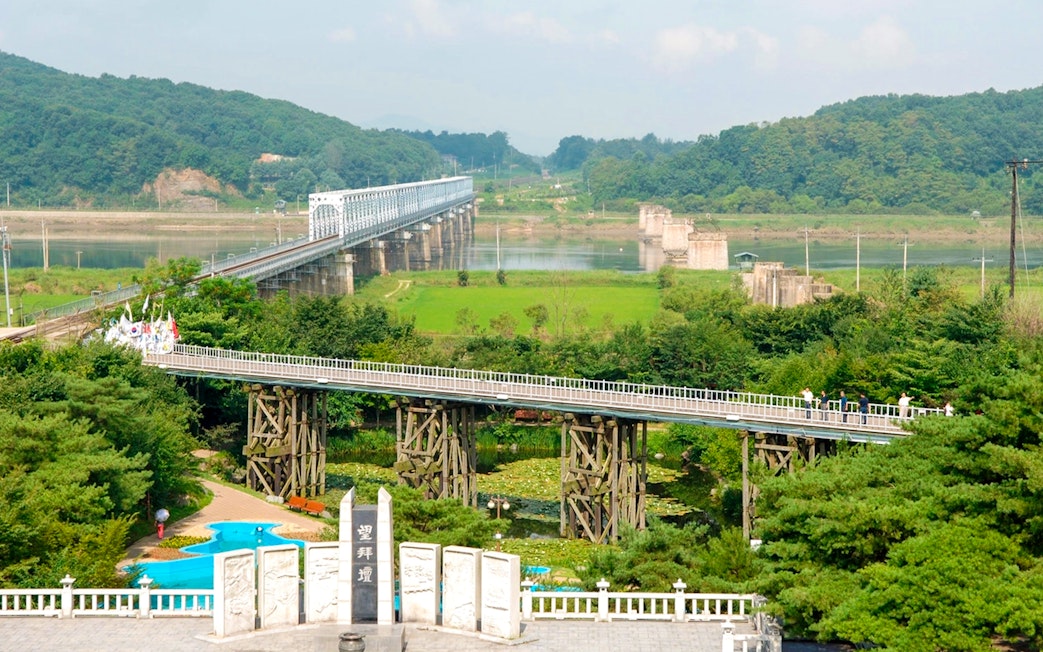 Freedom Bridge with Mangbaedan Altar in the foreground, surrounded by greenery.