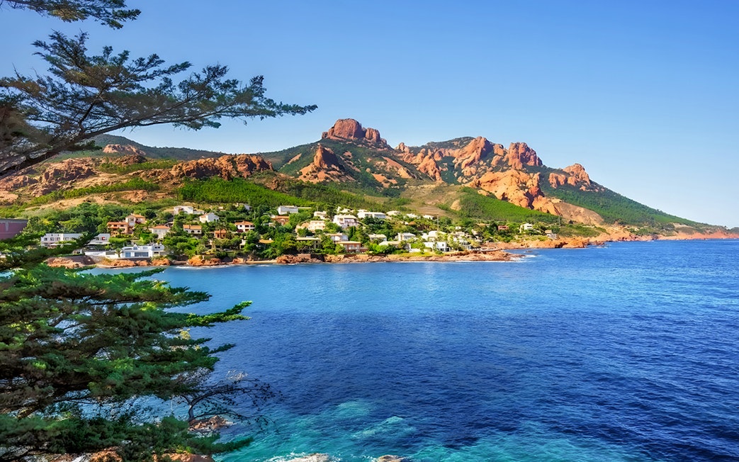 Coastal view of St Tropez with red cliffs and blue sea on the day tour from Nice.