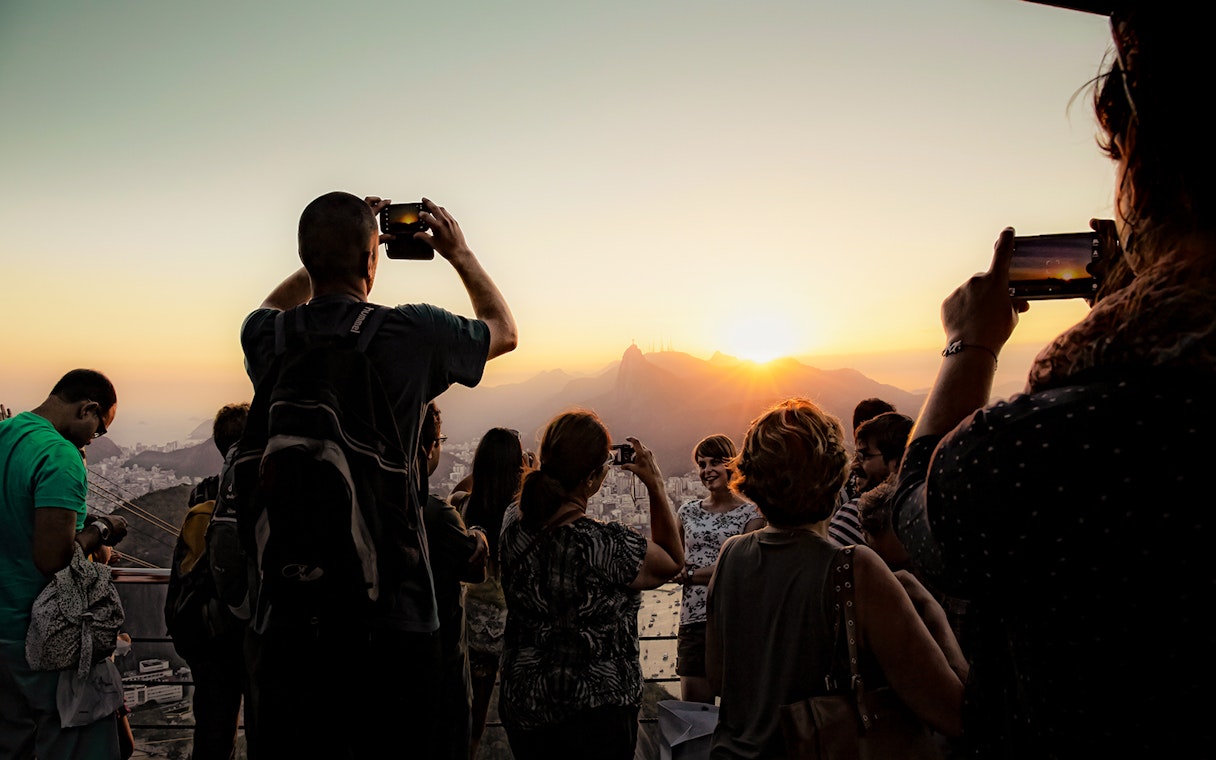 Tourists photographing sunset from Morro da Urca, Sugarloaf Mountain, Rio de Janeiro.