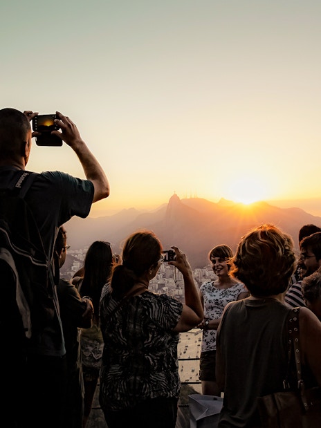 Tourists photographing sunset from Morro da Urca, Sugarloaf Mountain, Rio de Janeiro.