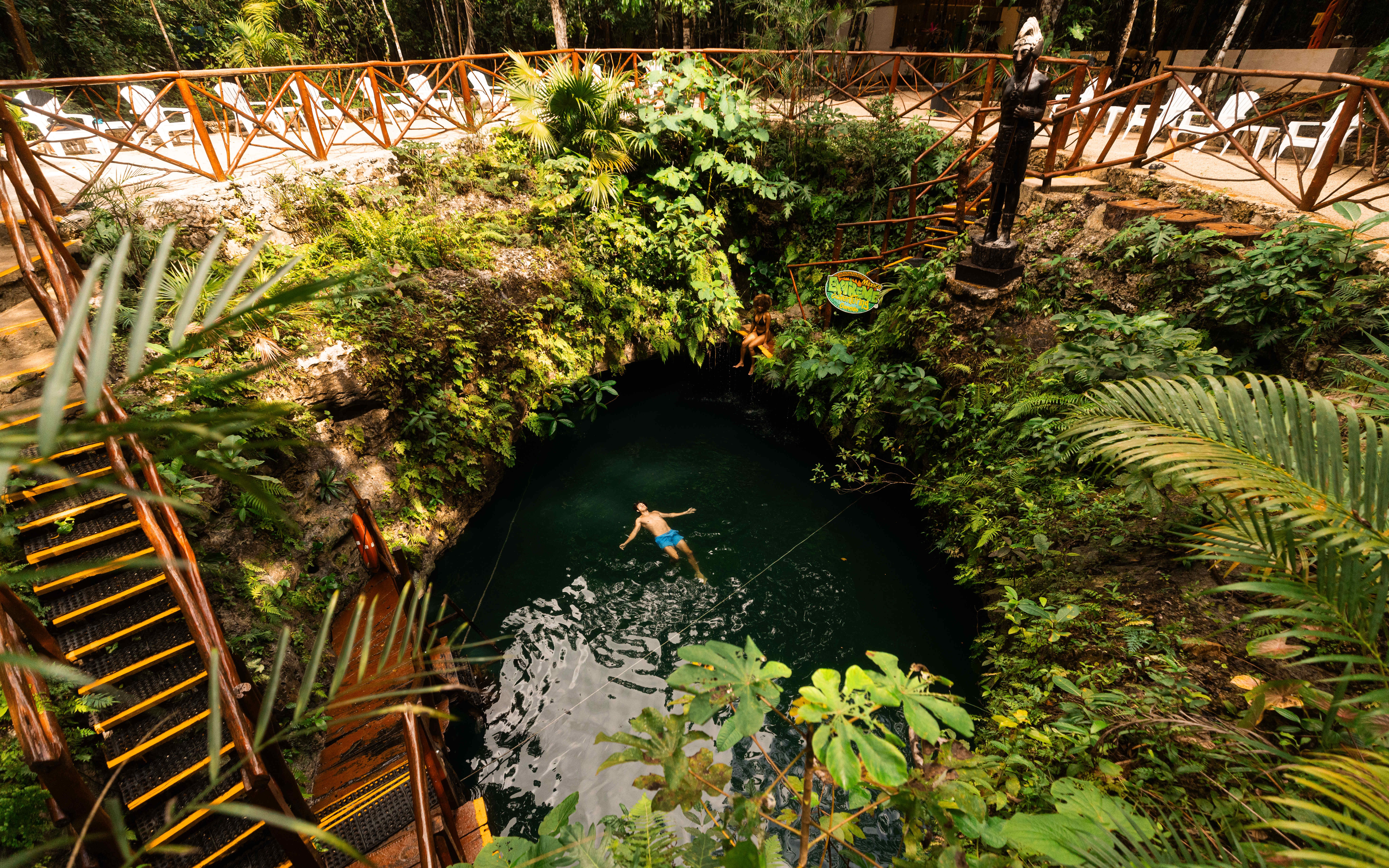 Couple relaxing in a lush cenote surrounded by greenery in Mexico.