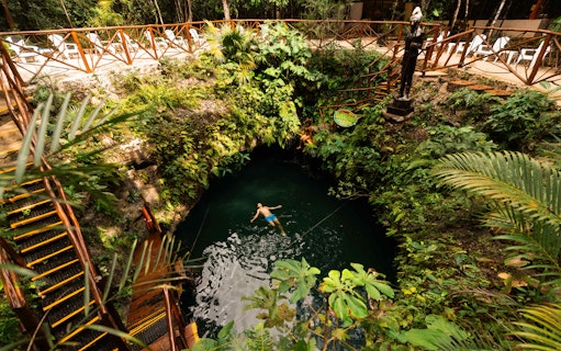 Couple relaxing in a lush cenote surrounded by greenery in Mexico.