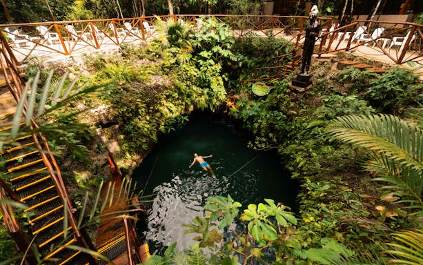 Couple relaxing in a lush cenote surrounded by greenery in Mexico.