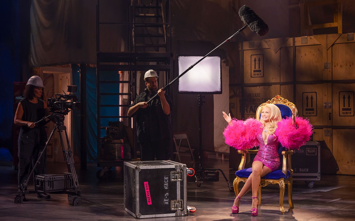 Woman in pink costume on set of "The Queen of Versailles" documentary, surrounded by film crew.