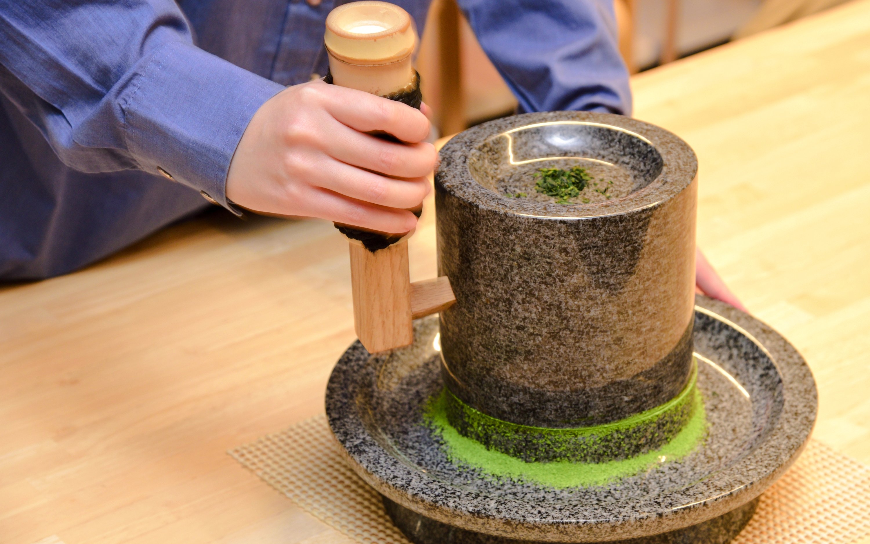 Grinding tencha leaves into matcha powder with a granite stone mill in Uji, Japan.