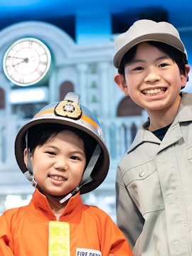 Children in firefighter and worker uniforms at Kidzania Tokyo.