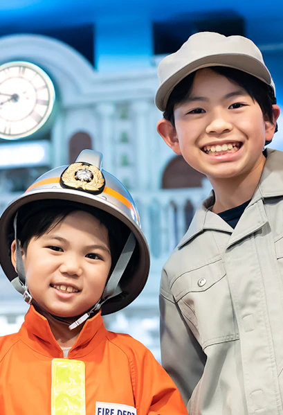Children in firefighter and worker uniforms at Kidzania Tokyo.