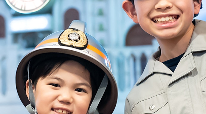 Children in firefighter and worker uniforms at Kidzania Tokyo.