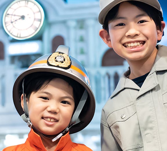 Children in firefighter and worker uniforms at Kidzania Tokyo.