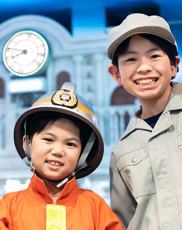 Children in firefighter and worker uniforms at Kidzania Tokyo.