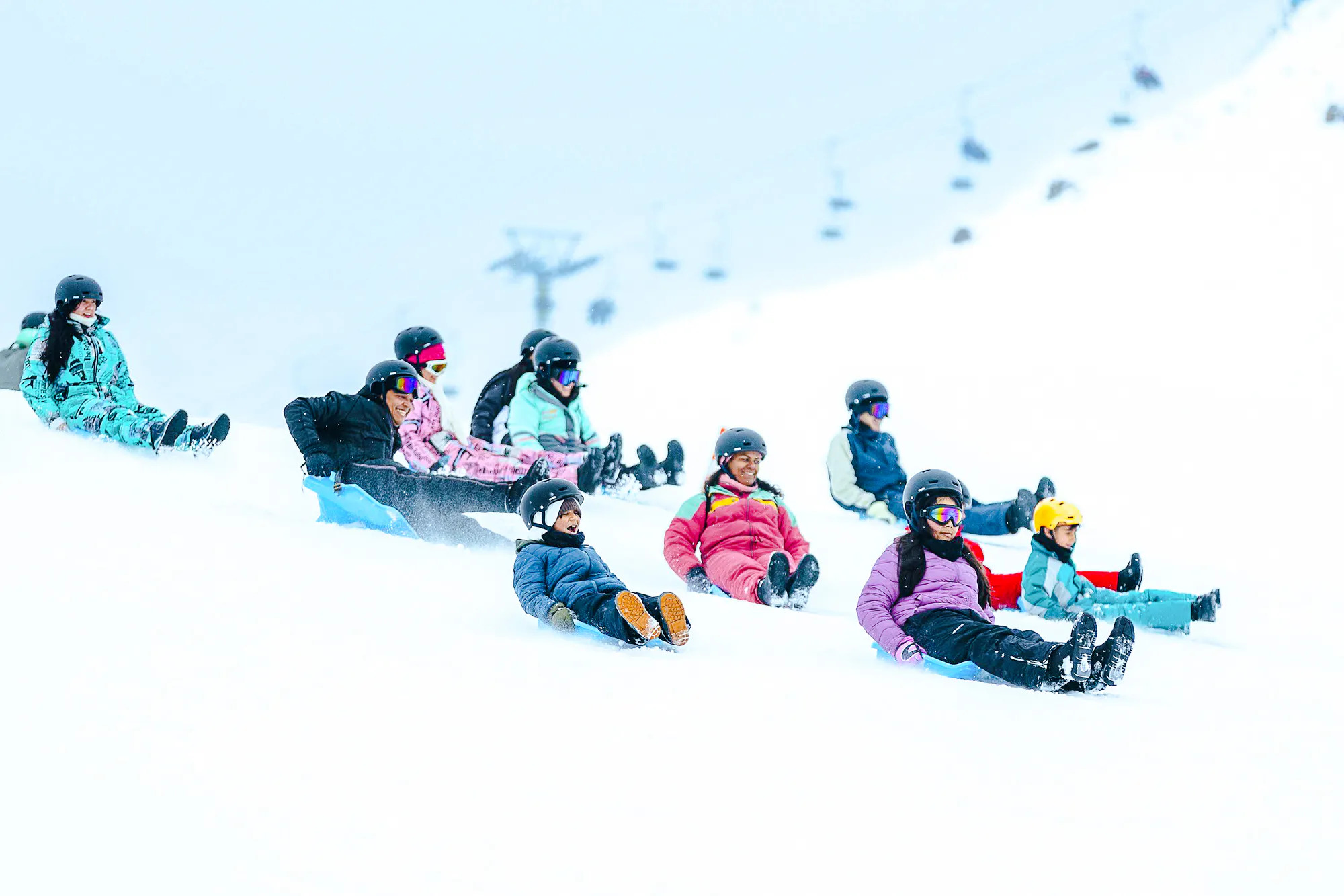 Visitors sledding down a snowy slope at Farellones Park, Santiago.