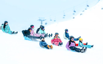Visitors sledding down a snowy slope at Farellones Park, Santiago.