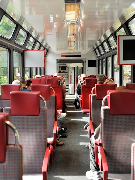 Passengers seated inside Zermatt shuttle train with Swiss Alps views through windows.