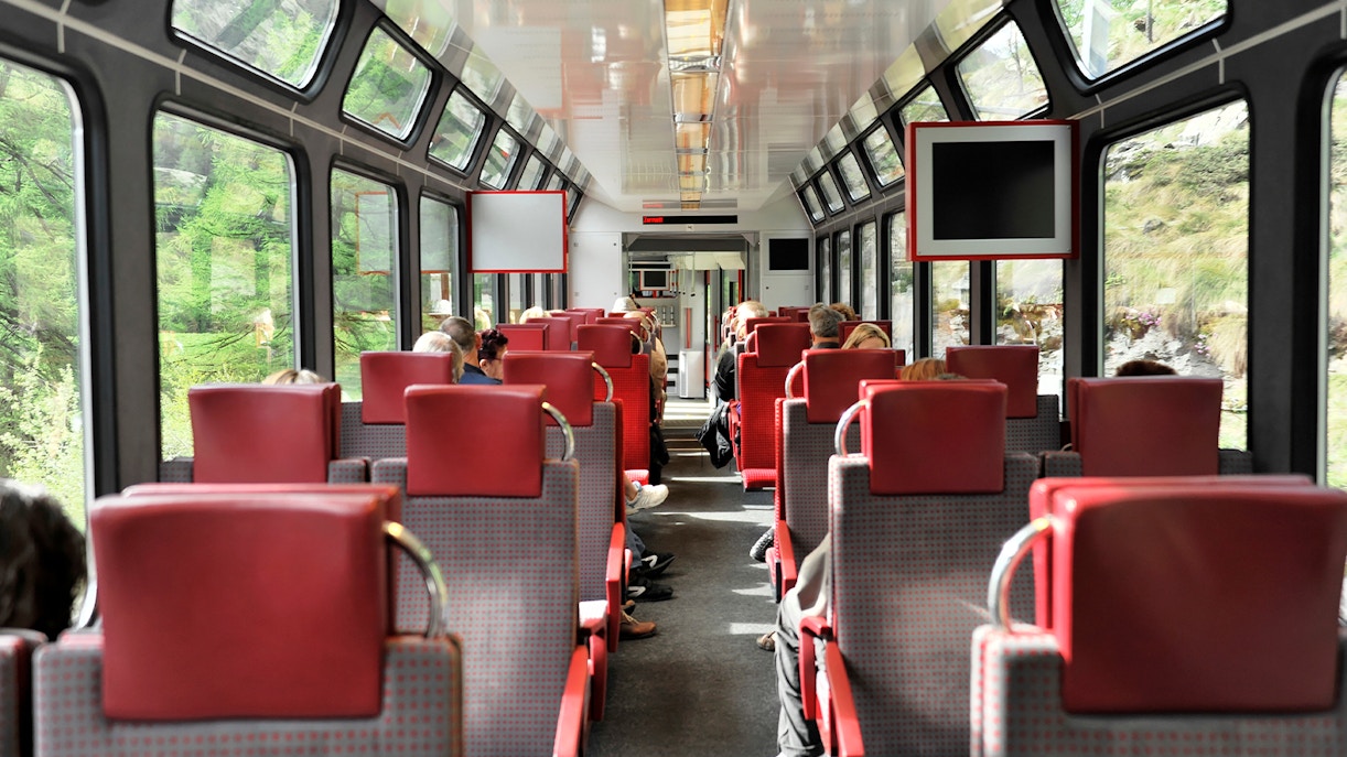 Zermatt shuttle train interior with passengers seated, viewing Swiss Alps.