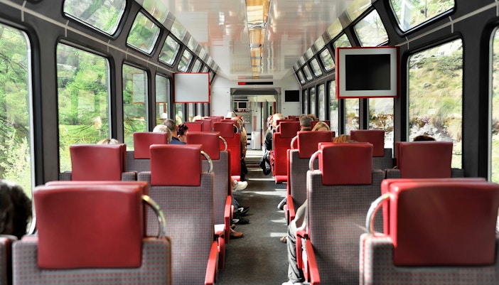 Zermatt shuttle train interior with passengers seated, viewing Swiss Alps.