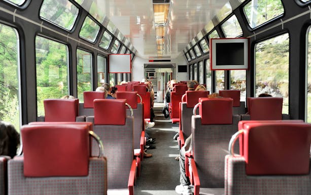 Passengers seated inside Zermatt shuttle train with Swiss Alps views through windows.