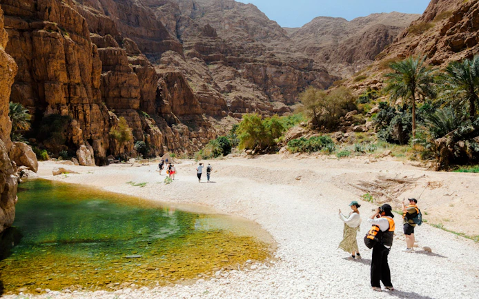 Visitors exploring rocky landscape near Wadi Shab, Oman.