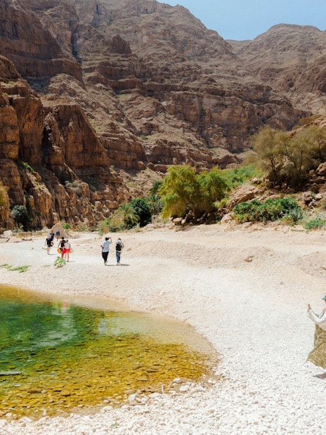 Visitors exploring rocky landscape near Wadi Shab, Oman.