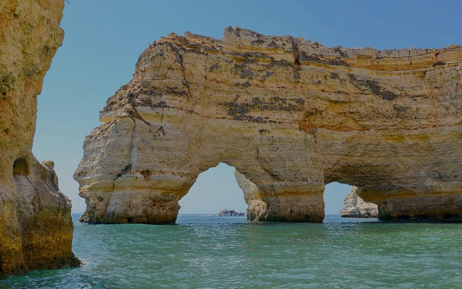 Boat approaching Benagil Caves' natural arches in Algarve, Portugal.