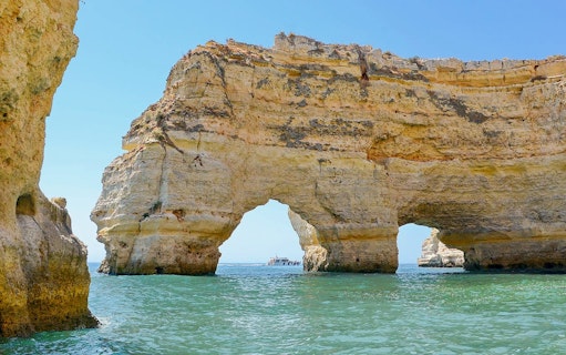 Boat approaching Benagil Caves' natural arches in Algarve, Portugal.