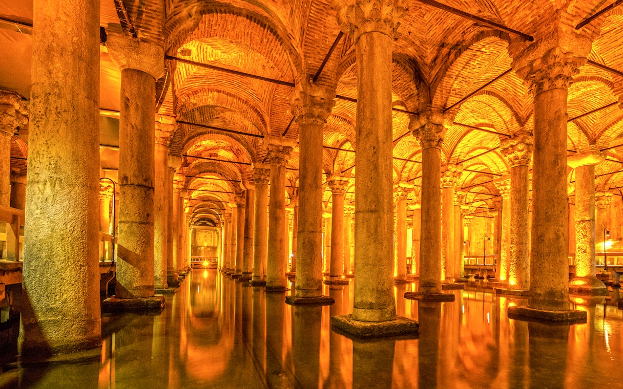 Ancient columns and arches inside the illuminated Basilica Cistern in Istanbul.