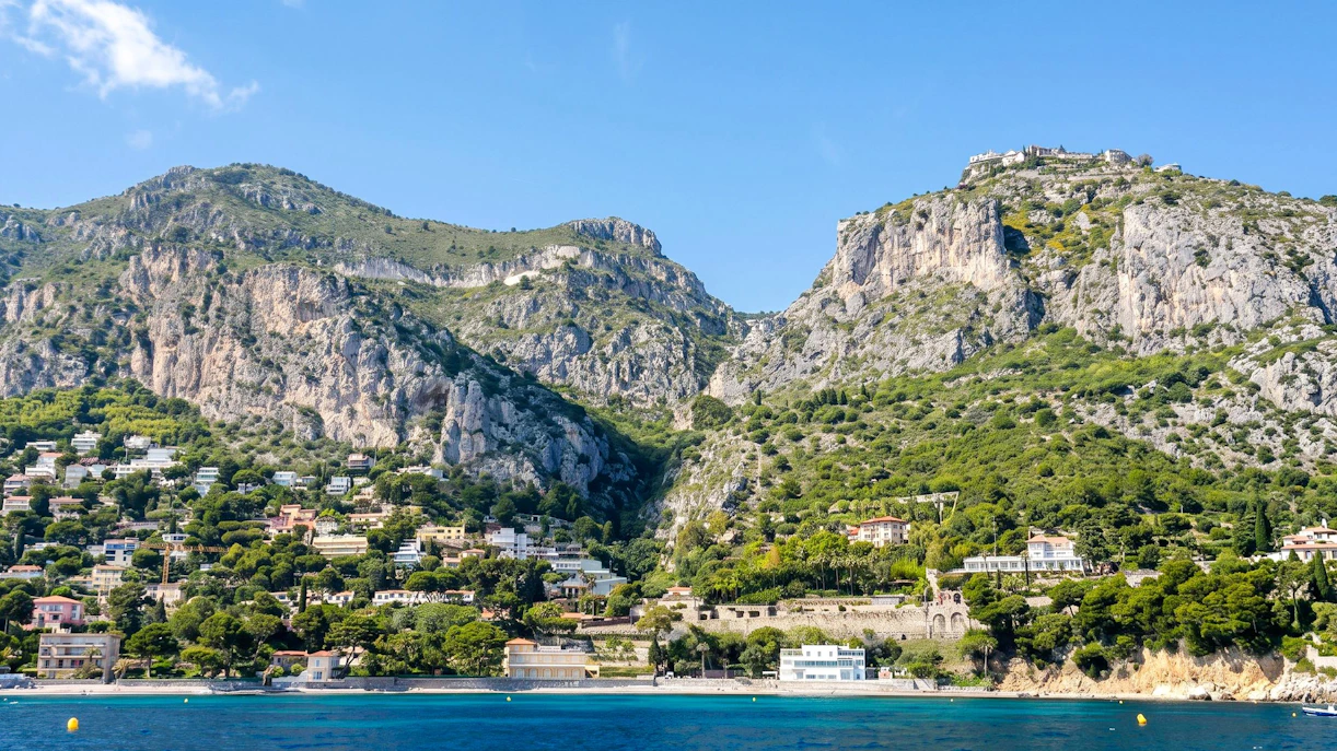 Villefranche coastline with hillside homes and cliffs on a boat tour to Monaco.