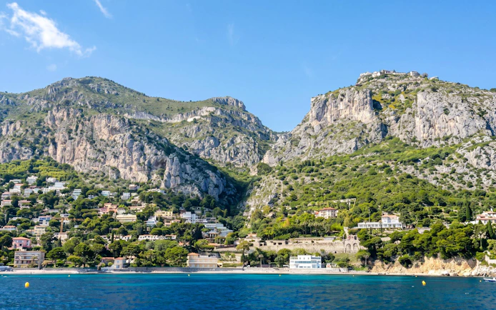 Villefranche coastline with hillside homes and cliffs on a boat tour to Monaco.