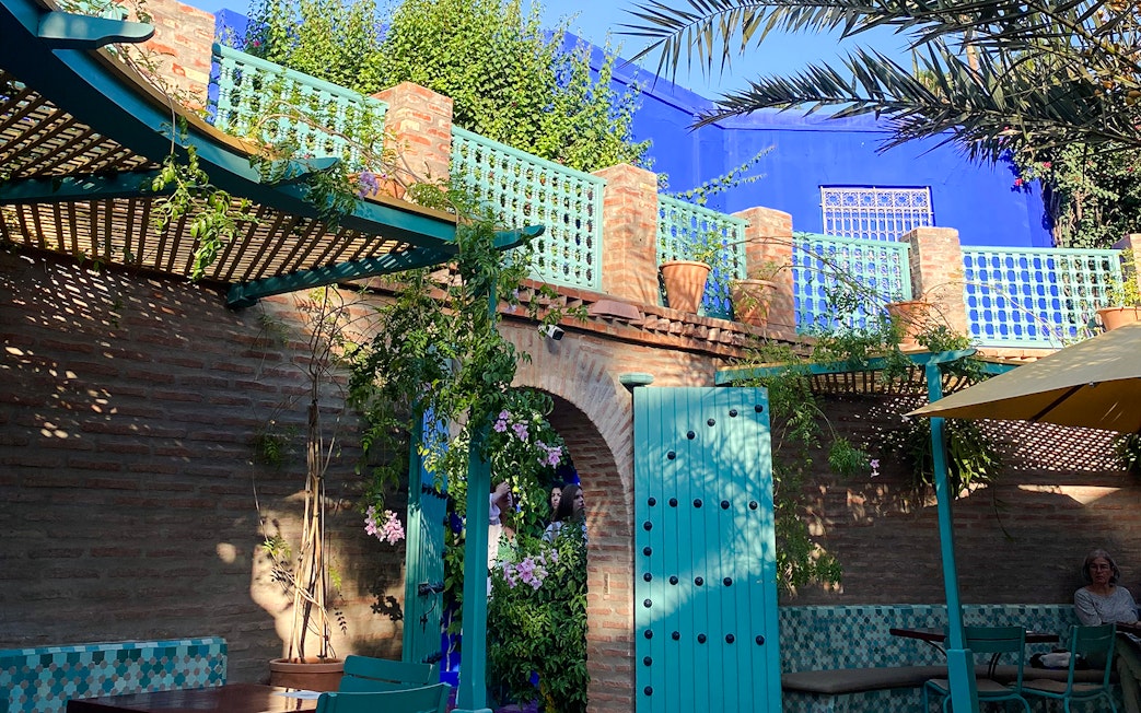 Jardin Majorelle courtyard with blue doors, brick walls, and lush greenery.