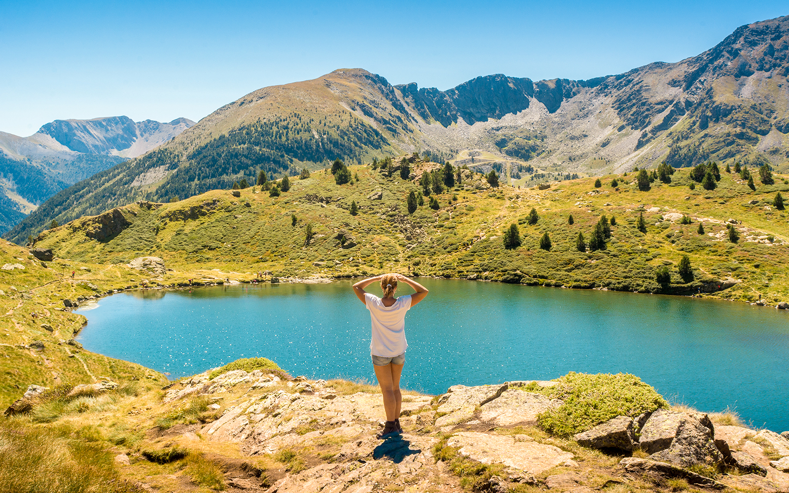 Person overlooking a mountain lake in Andorra with ski lifts in the distance.