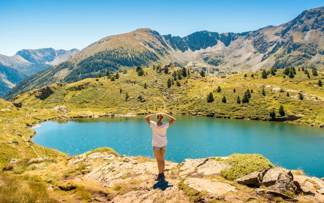 Person overlooking a mountain lake in Andorra with ski lifts in the distance.