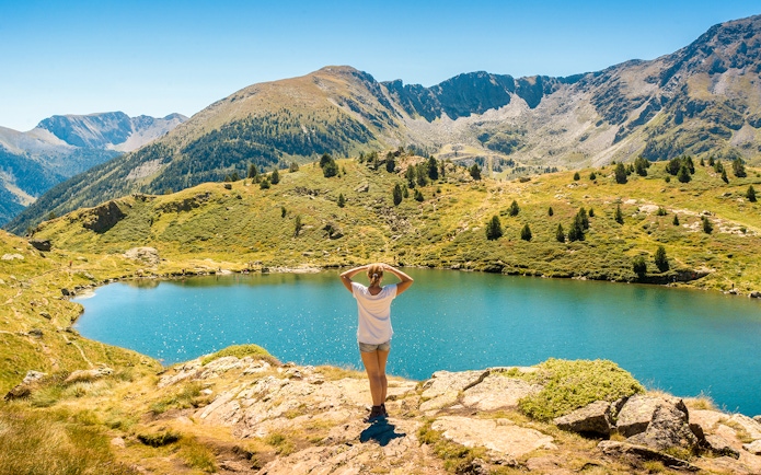 Person overlooking a mountain lake in Andorra with ski lifts in the distance.