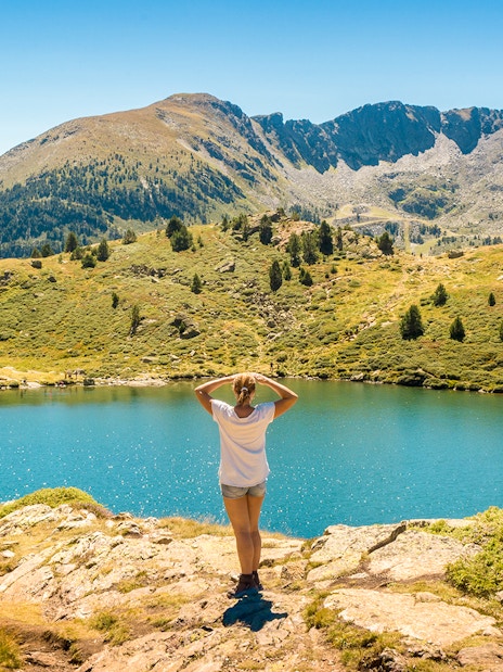 Person overlooking a mountain lake in Andorra with ski lifts in the distance.