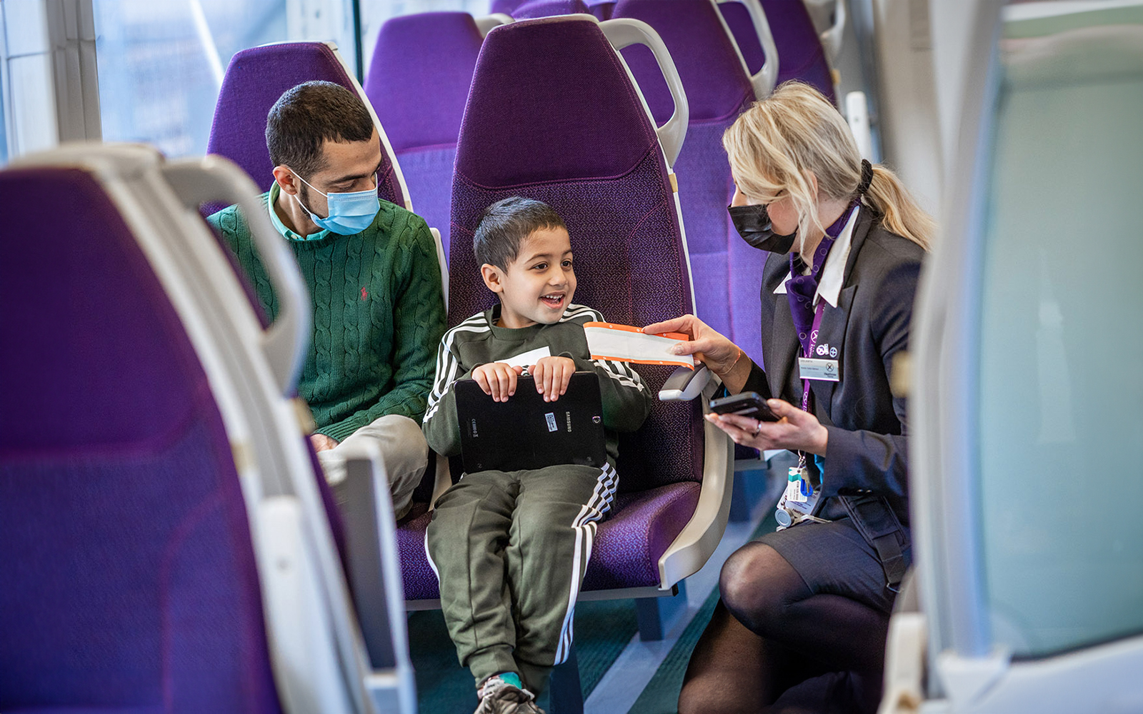 Train staff checking ticket of seated passengers.