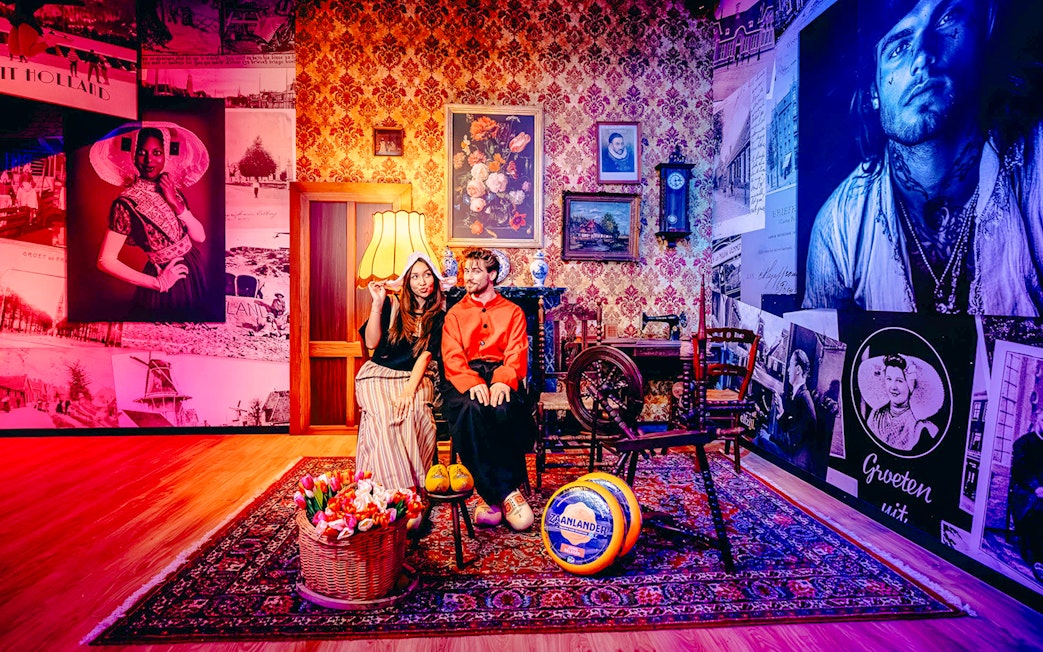 Guests in traditional Dutch attire in a Holland-themed room with tulips and cheese.