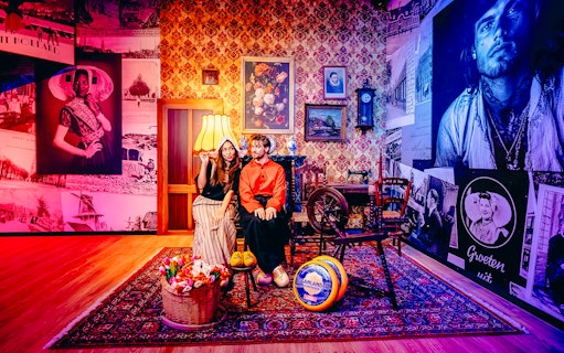 Guests in traditional Dutch attire in a Holland-themed room with tulips and cheese.