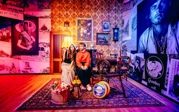 Guests in traditional Dutch attire in a Holland-themed room with tulips and cheese.