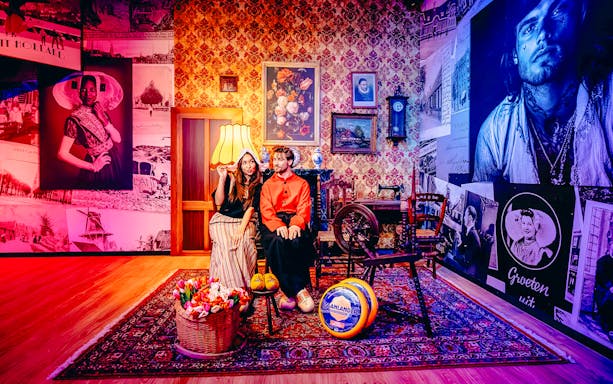 Guests in traditional Dutch attire in a Holland-themed room with tulips and cheese.