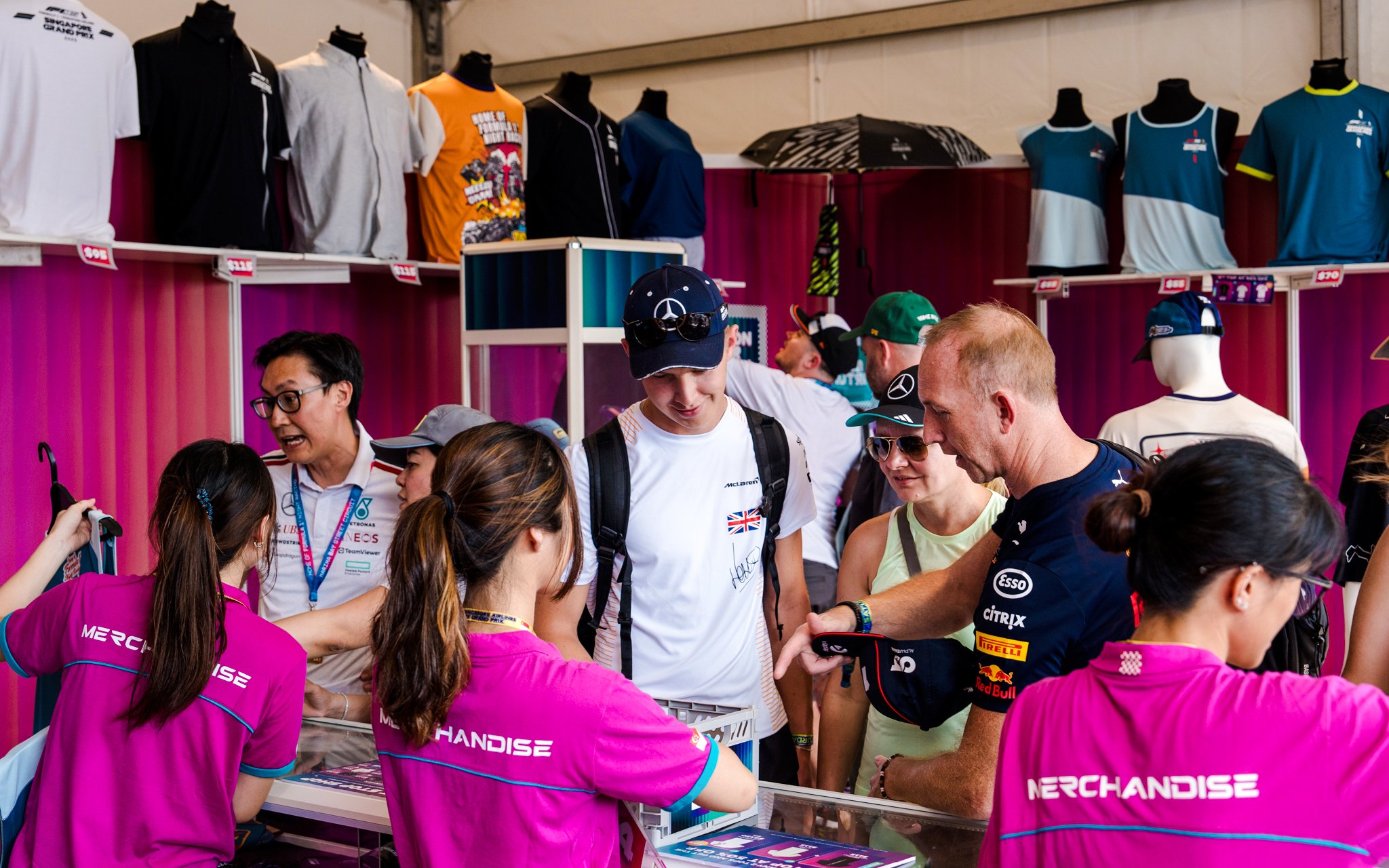 Customers browsing merchandise including tees and caps at a sports event booth.