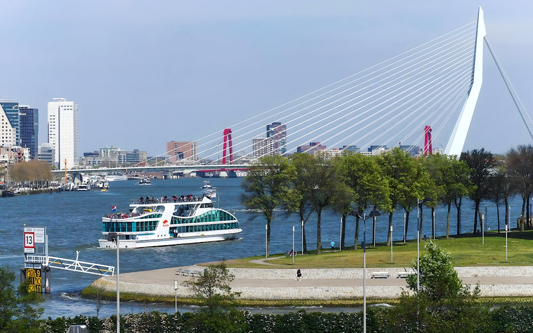 Harbor cruise boat on Rotterdam's river with Erasmus Bridge in the background.