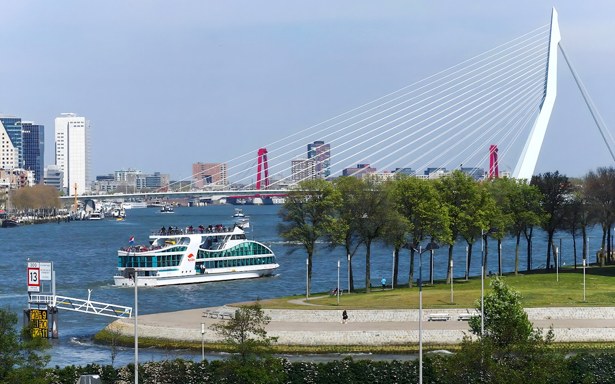 Harbor cruise boat on Rotterdam's river with Erasmus Bridge in the background.