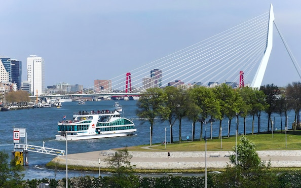 Harbor cruise boat on Rotterdam's river with Erasmus Bridge in the background.