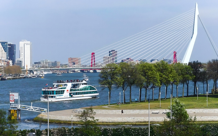 Harbor cruise boat on Rotterdam's river with Erasmus Bridge in the background.